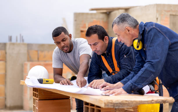 istock Construction workers looking at a blueprint and sharing ideas at a building site 2183863079