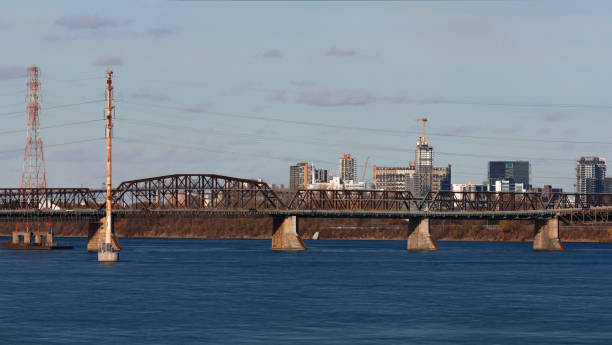 Panoramic view of the Victoria Bridge crossing the St. Lawrence River, with Montreal and Longueuil on a clear day. Showcases Quebecs iconic infrastructure and urban landscape.
