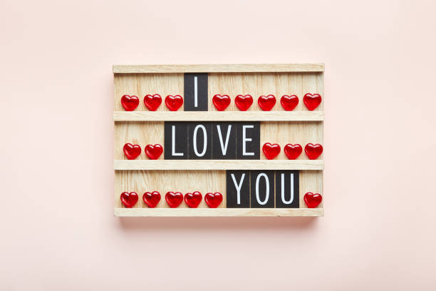 I love you. Text in letter board with red hearts on pink background. Top view. Background for Valentine's day.