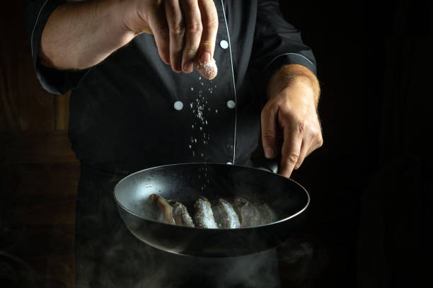 istock In a dimly lit kitchen, a chef expertly sprinkles salt over fresh shrimp in a hot pan, creating an inviting atmosphere filled with anticipation of delicious flavors 2183876398