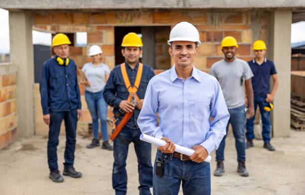 istock Civil engineer smiling with a group of construction workers at a building site 2183878777