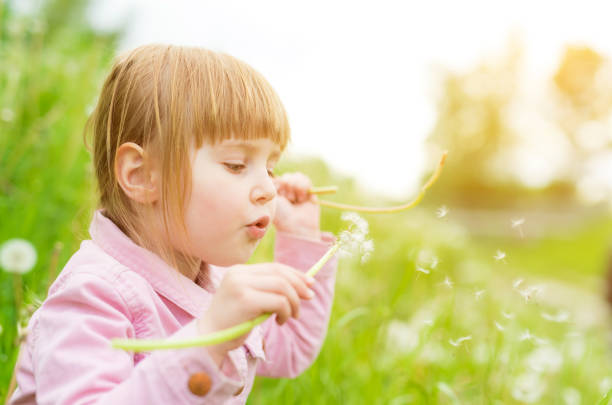 istock cute little girl blowing off dandelions 2183879200