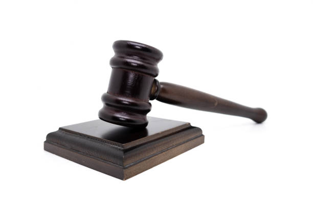 DARK JUDGE GAVEL ON THE TABLE IN THE COURTROOM AND LAW BOOKS IN THE BACKGROUND. CLOSE UP VIEW. FOCUS SELETED.