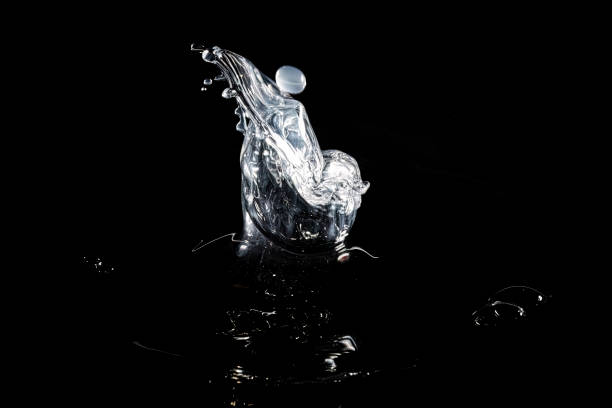 Macro picture of a drop falling into water creating different formations iluminated with colored light
