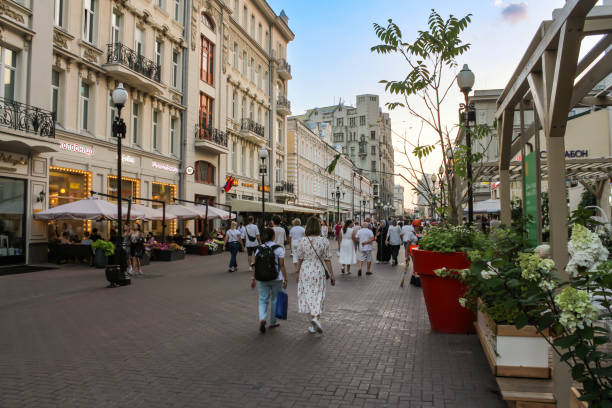 Moscow, Russia - 27, August, 2024.\nEvening walk along the legendary old Arbat.\nGroups of people walking along Arbat between outdoor cafes.