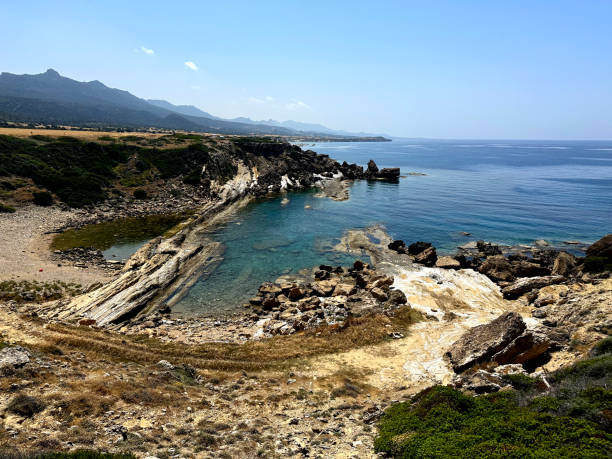 istock The serene coastline features rocky formations and clear blue waters, framed by rolling hills under a bright sky. A peaceful retreat ideal for nature lovers 2183897400