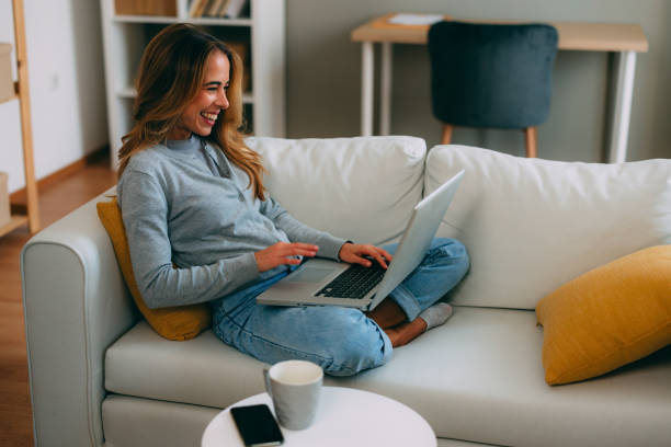 istock Smiling woman working from home using laptop on sofa 2183898121
