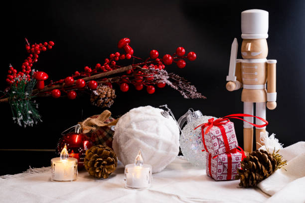 White and red christmas decoration table including nutcracker, snowy christmas balls, candles, red berries and gifts