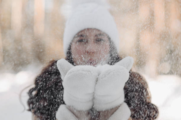 A young girl in a red beanie lies in the snow, her piercing blue eyes reflecting the crisp winter light.
