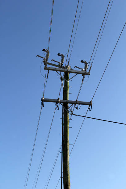 istock Wooden power electricity pole with multiple wires and insulators against a clear blue sky 2183919363