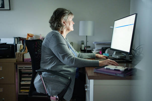 Senior Woman Working at a Computer in Home Office Setting