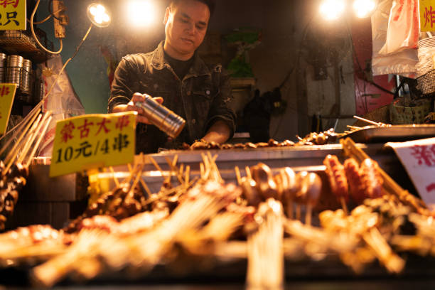 Guilin, Guangxi Province, China, 22 October 2024, Guilin Food Street is a busy and popular for all types of local street food. Bbq meat man cooking up delicious skewers of meats.