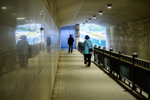 Two people walking on the highway underpass.