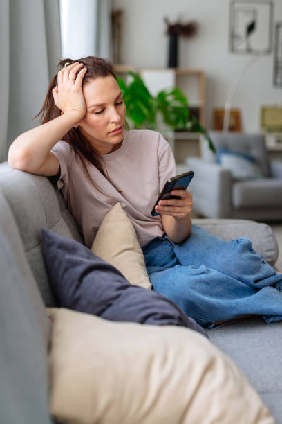 istock Woman looking at smartphone screen, sitting on couch 2183945098
