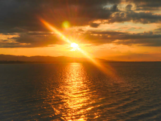 Sunset over the lake with dramatic clouds and mountains in the background