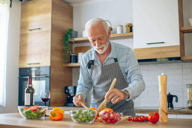 istock Senior man in kitchen cooking healthy meal 2183948527