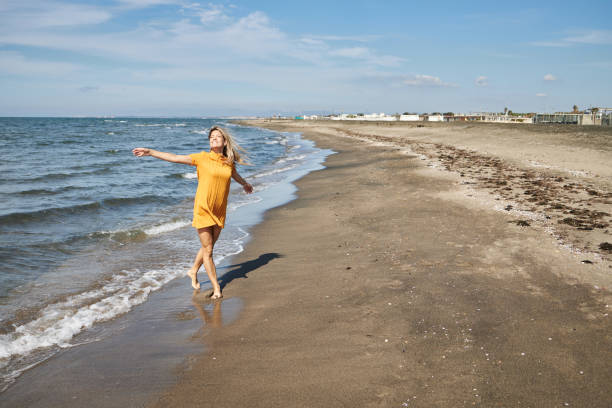 Happy woman enjoying day on a beach. It’s autumn and sun, perfect combination for vacation!