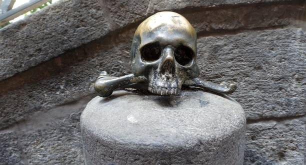 A lucky metal skull with crossbones on a stone in the old town center.