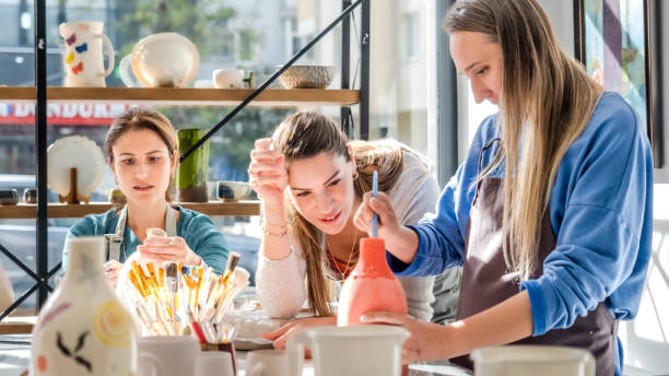 istock In an art studio with an environment adorned with artistic paintings in the background, three beautiful middle-aged women friends are happily drawing patterns and painting the vases they made from clay at a table filled with art supplies 2183971728