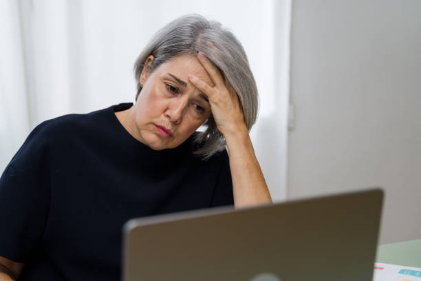 istock Stressed senior woman having headache while working on laptop at home 2183975945