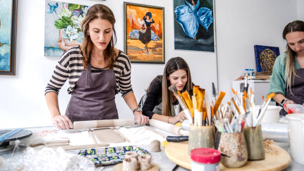 istock In an art studio with an environment adorned with artistic paintings in the background, three beautiful middle-aged women friends are happily drawing patterns and painting the vases they made from clay at a table filled with art supplies 2183981963