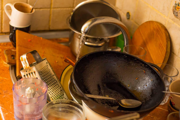 istock stack dirty plates with forks, cups, stand near kitchen sink, in kitchen with white facades. Unwashed dishes in pile on kitchen table near sink 2183988011
