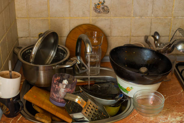 istock stack dirty plates with forks, cups, stand near kitchen sink, in kitchen with white facades. Unwashed dishes in pile on kitchen table near sink 2183988107