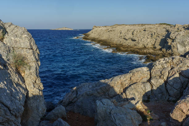 istock Breathtaking coastal cliffs with azure waves under a clear sky at sunset on a tranquil shore. 2183997224