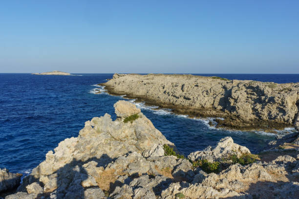 istock The sun rises over the horizon, casting a soft light on rocky cliffs that meet the clear blue sea, evoking peace 1 2183997250