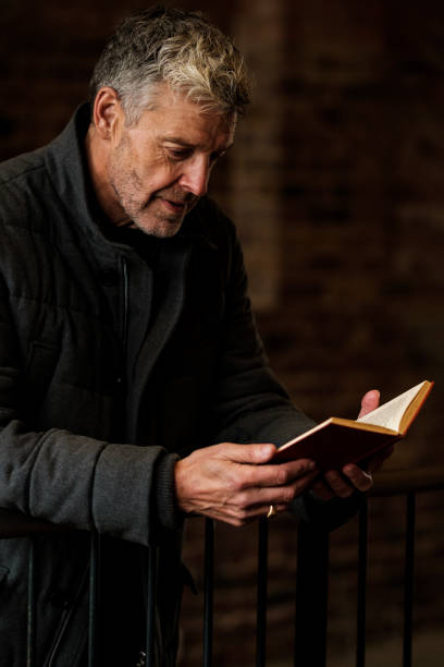 istock Senior professor reading a book in university hallway 2183998495