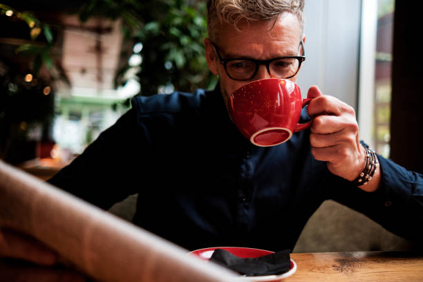 Businessman drinking coffee and reading newspaper in cafe