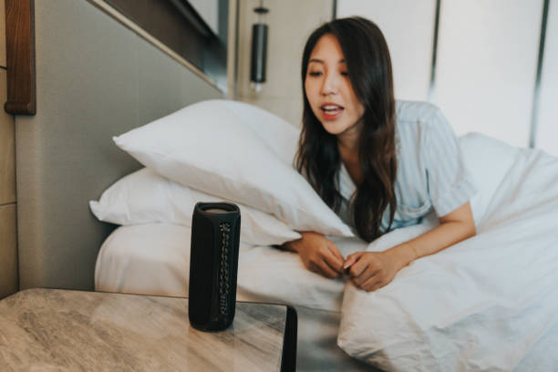 istock Asian girl is in a room and using smart home techonology with speech recognition on speaker and mobile app 2184005439