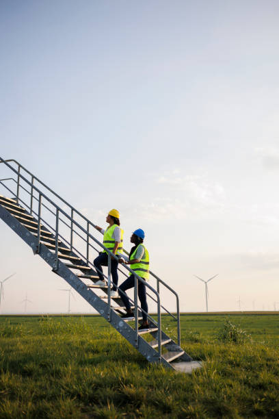 istock Two Female Engineer wearing uniform ,helmet hold document inspection work in wind turbine farms rotation to generate electricity energy 2184016464