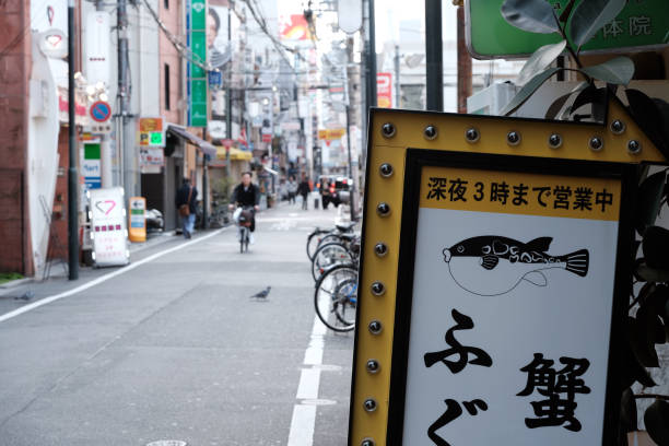 Cyclist on a street in Shinsaibashi, a district in the Chūō-ku ward of Osaka, Japan and the city's main shopping area, adjacent to Dotonbori.