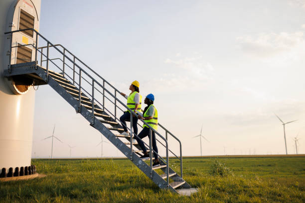 istock Two Female Engineer wearing uniform ,helmet hold document inspection work in wind turbine farms rotation to generate electricity energy 2184016753