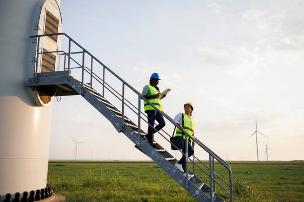 istock Two Female Engineer wearing uniform ,helmet hold document inspection work in wind turbine farms rotation to generate electricity energy 2184016868