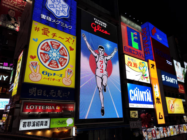 View of the Glico Man, a huge, brightly lit sign glowing over the Dotombori canal in Osaka‘s entertainment district for more than 80 years, depicting a giant athlete on a blue track. The sign is just west of Ebisubashi.