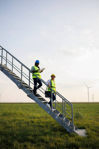 istock Two Female Engineer wearing uniform ,helmet hold document inspection work in wind turbine farms rotation to generate electricity energy 2184016920