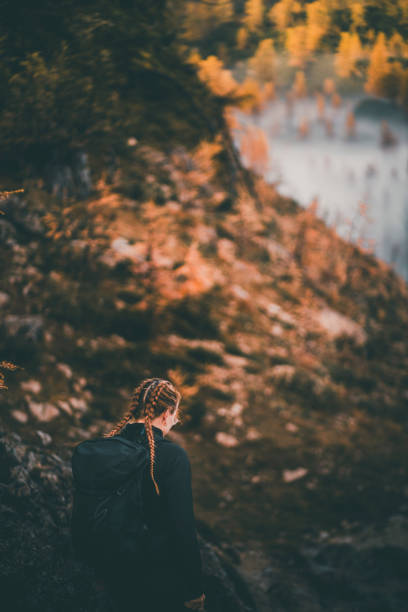 Young woman backpacks through Larch forest in autumn, Slovenian Alps