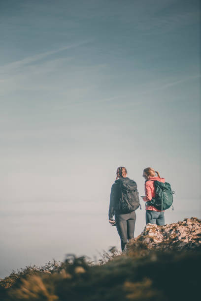 Young women backpackers stand on mountain top in autumn, Slovenian Alps