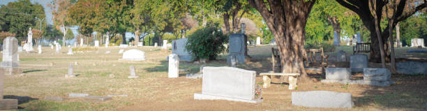 Panorama view tree shaded cemetery, burial ground, gravesite, graveyard with gravestone tombstone markers headstone, elaborate stone slab funeral, green space memorial park, Farmers Branch, Texas. USA