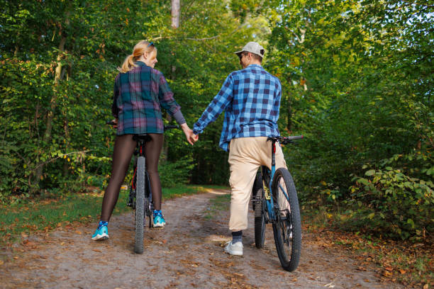 istock Young couple on bicycles holding hands on a forest road 2184024708