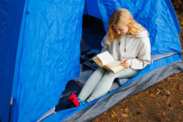 istock Woman reading a book while sitting in a tent alone with nature 2184025938