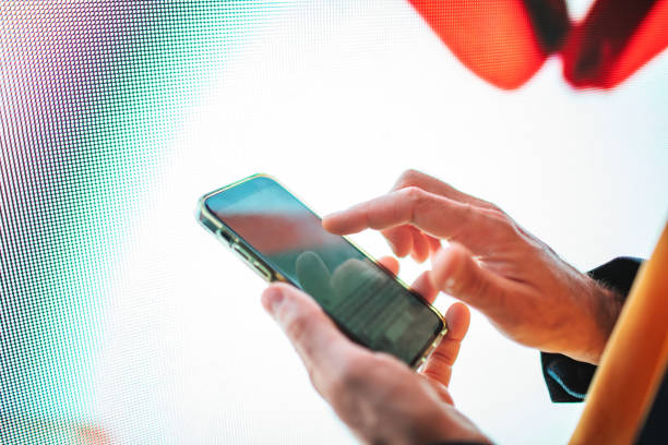 istock Closeup of mobile in hands with neon light billboard at background 2184036094