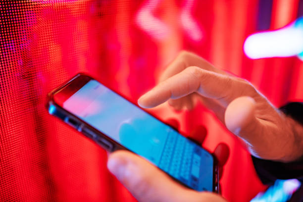 Closeup of mobile in hands with red light billboard at background