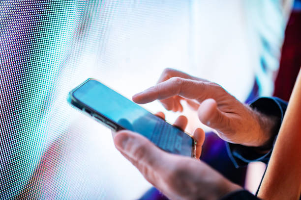 istock Closeup of mobile in hands with neon light billboard at background 2184036099
