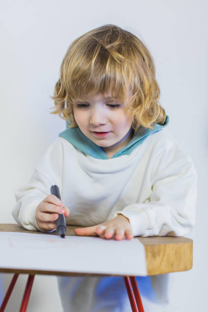 Boy drawing on paper with felt-tip pen