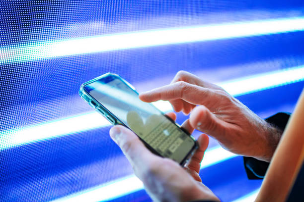 Closeup of mobile in hands with blue light billboard at background