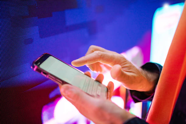 istock Closeup of mobile in hands with neon light billboard at background 2184036269