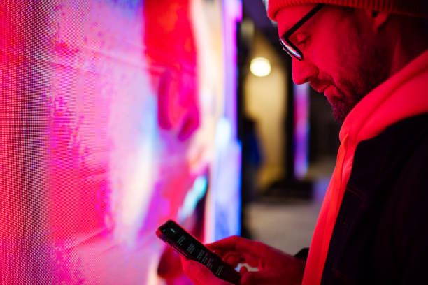 istock Mid adult man using mobile at night while standing by neon lights 2184036270